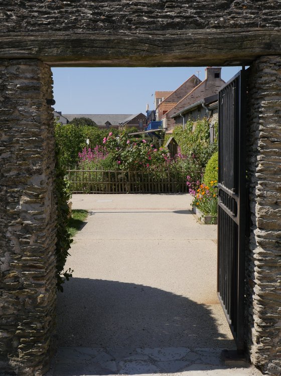 L'entr&eacute;e de l'&Eacute;co-Domaine La Fontaine : un porche de pierre ouvert sur le jardin fleuri